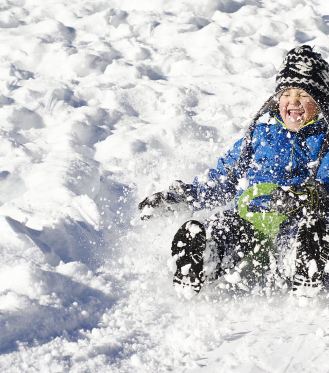 Enfant aspergé de neige en faisant de la luge
