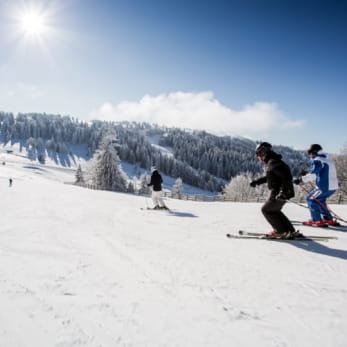 Famille qui dévale les pentes de ski alpin à Métabief