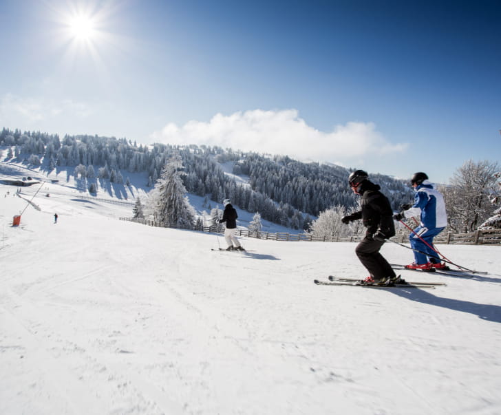 Famille qui dévale les pentes de ski alpin à Métabief
