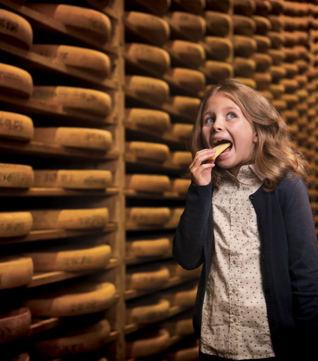 Fillette en train de déguster du comté dans une cave d'affinage